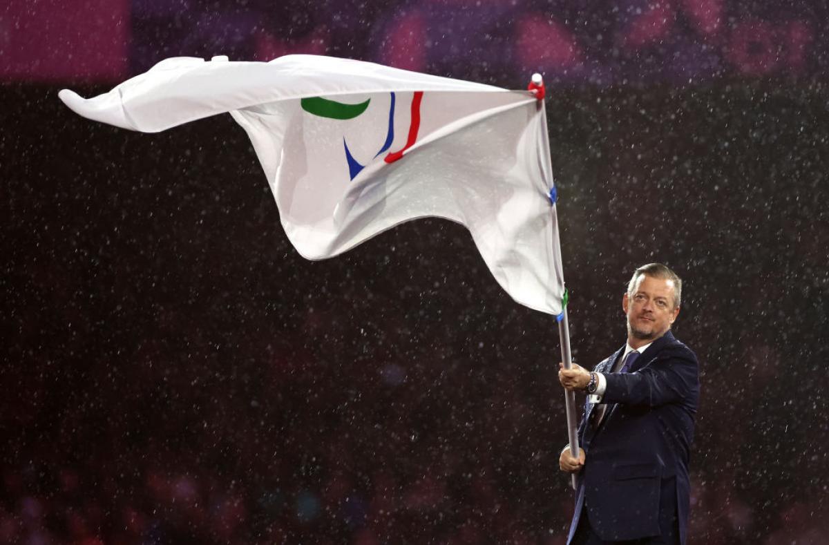 Andrew Parsons waves the flag of with the Paralympic symbol